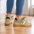 Stylowe zielone sneakersy na parkiecie.png