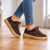 Brązowe sneakersy na drewnianej podłodze.png