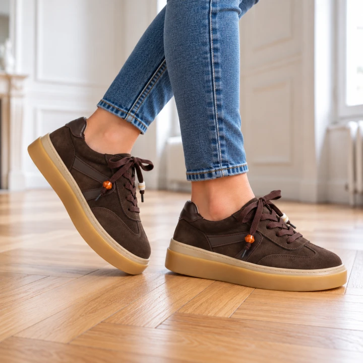 Brązowe sneakersy na drewnianej podłodze.png